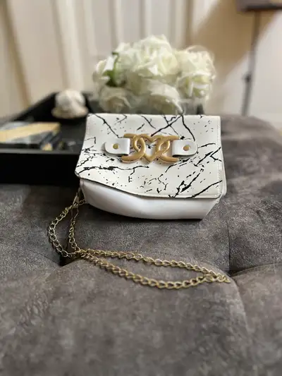 This chic, gently bag features a marble-patterned design with gold-tone hardware and a chain strap,...