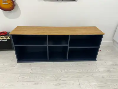 A blue stv stand with an oak top holds a flat-screen tv, books., View more