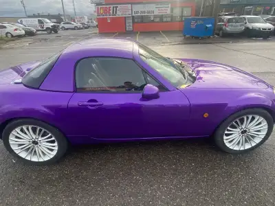 Feast your eyes on this vibrant, one-of-a-kind purple Mazda Miata, a sporty convertible that's sure...