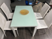 Fine Glass top dining table with 4 white chairs.