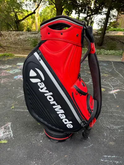 This is a used TaylorMade tour staff golf bag featuring a sleek red and black design, perfect for ca...