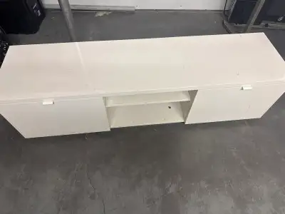 This is a white TV stand with two doors and a shelf in the middle. It's perfect for a small living r...