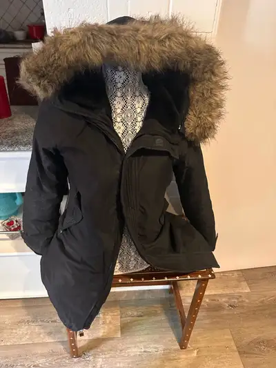 This is a used TNA black winter parka in size small, featuring a faux fur-trimmed hood and a warm, i...
