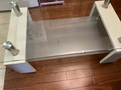 This sleek glass coffee table features a sturdy construction with a glass top and white wooden suppo...