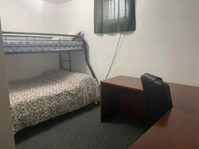 The room includes a bed and a desk. It has a shared kitchen/dining room, living area, bathroom, in-u...