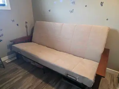 This is a sturdy futon, perfect for extra seating or as a guest bed, featuring a comfortable beige c...