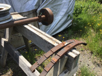 Trailer axle with rims and leaf springs.