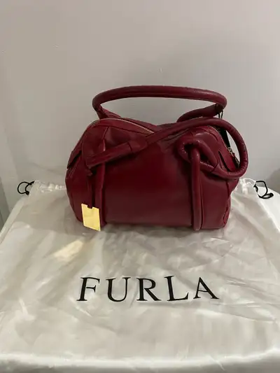 “YES IT IS AVAILABLE “ This is a stylish, used FURLA leather satchel, crafted in Italy, featuring a...