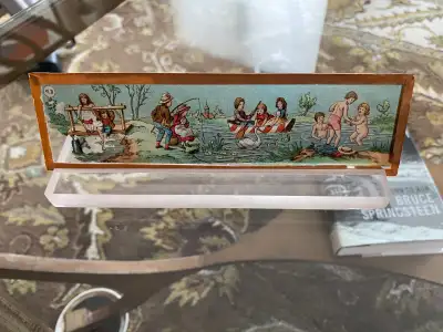 Antique glass slide depicting young children fishing and frolicking in the water. Marked EP in the r...