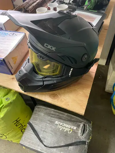 This is a used CKX helmet with yellow tinted goggles, perfect for winter activities such as snowmobi...