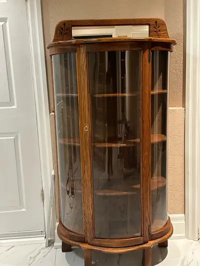Beautiful solid wood display cabinet with curved glass front and sides. Features detailed wood carvi...
