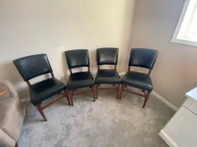 Chairs 4 black leatherette on brown wood No tears great for poker table Call or text Shawn at 403 99...