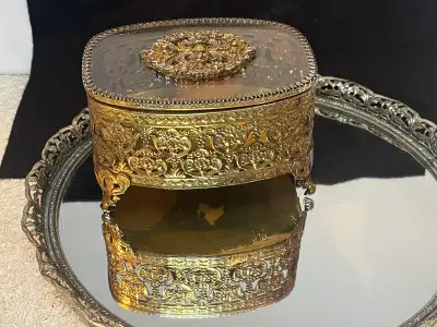 This vintage jewelry casket is made of metal with a gold finish . Slightly beveled glass hinged lid...