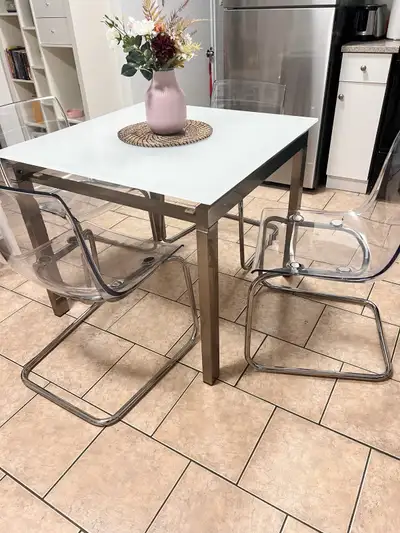 Selling a modern dining table set! The table features a square glass top and a sleek metal frame. It...
