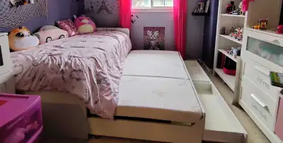 White twin bed with a pull-out trundle, perfect for a child's bedroom. Features a wooden slat suppor...