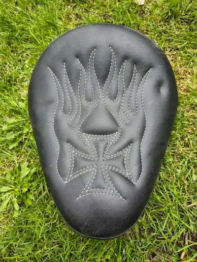 Custom solo motorcycle seat featuring an Iron Cross and flame stitched design, typically used for ch...