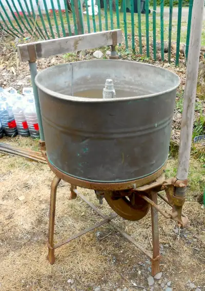 Ancienne laveuse à linge avec mécanisme fonctionnel, peut-être convertie an bac de jardinage. La pla...
