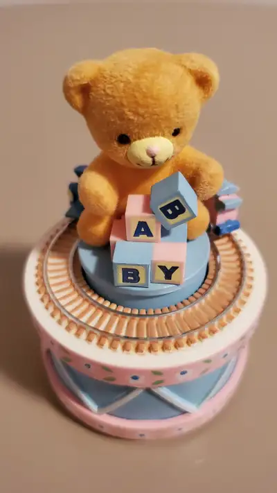 This cute music box features a toy train that revolves around a bear sitting on a drum and playing w...