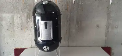 WEBER charcoal smoker grill comes with Weber cover, partial bag of charcoal and partial bag of wood...
