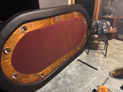 This spacious, custom-built oval poker table features integrated metal cup holders and a durable fel...