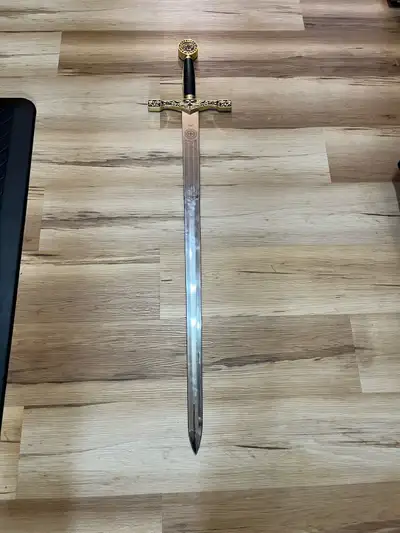 This is a decorative Excalibur King Arthur sword replica featuring a gold-plated guard and pommel. T...