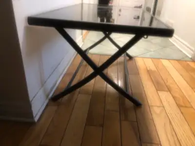 This is a used folding table with a sleek black top and matching black metal legs, perfect as a side...