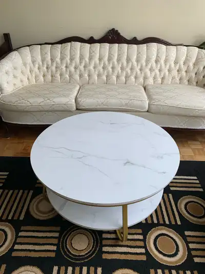 MOVING SALE: This round, two-tier coffee table features a faux marble top and gold legs, perfect for...
