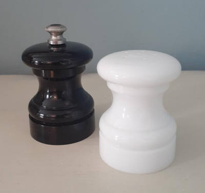 This vintage 1982 set from Peter Piper includes a white salt shaker and black peppermill in heavy, g...