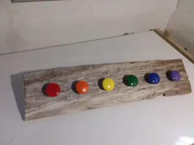 Handcrafted Coat Rack. 6 colourful knobs mounted on a 100 year old barn board rail. 22" L x 5 1/2" H...