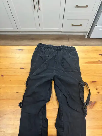 These are Nova Men black cargo pants, featuring a comfortable elastic waistband and stylish straps....