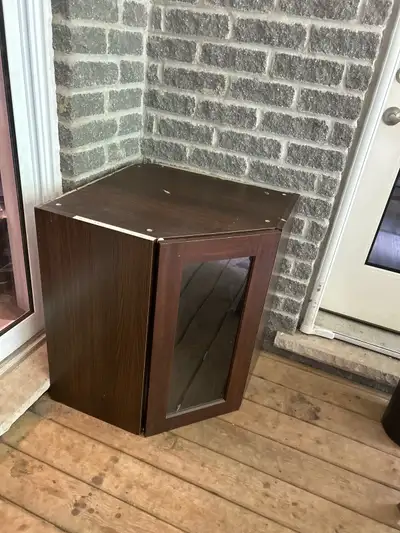 This is a brown corner cabinet with a glass door, perfect for adding a touch of elegance and storage...