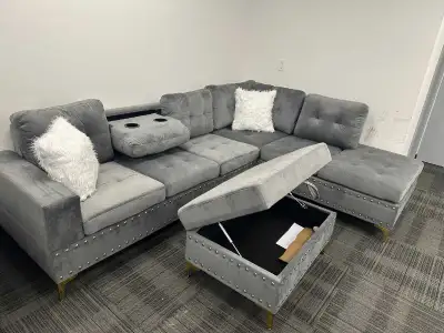 This brand new one grey sectional sofa features a stylish design with studded trim and includes a st...