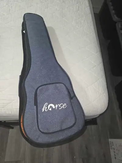 This is a Horse brand ukulele case. It includes a brown bass ukulele. The ukulele has four strings a...
