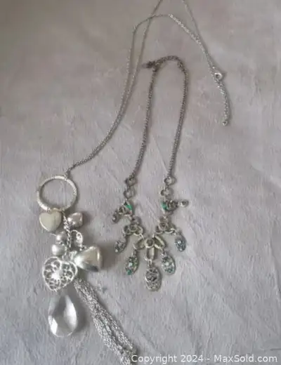 Lot of 2 costume jewelry necklaces. 1 long necklace w/ several dangle charms& 1 large crystal. 1 nec...