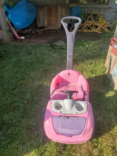 Pink car. Kid sits and you push. Two cup holders. Storage in front. Buckle and strap still good. Pic...