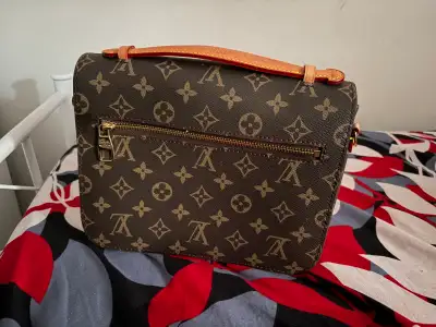 This is a Louis Vuitton bag with the iconic monogram pattern, featuring a structured silhouette and...