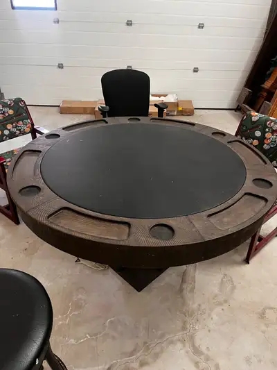 This is a used poker table made with solid wood. The table features a padded playing surface and ind...