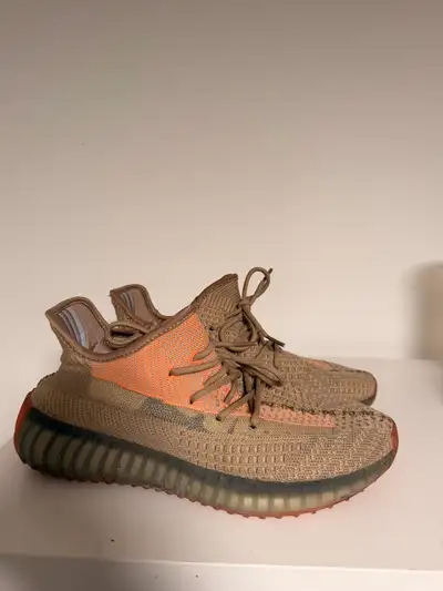These Adidas Yeezy Boost 350 V2 sneakers feature a distinct earth-toned knit upper with a bold orang...