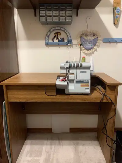 This is a Singer 4-thread professional serger with differential feed, mounted in a sturdy cabinet, p...