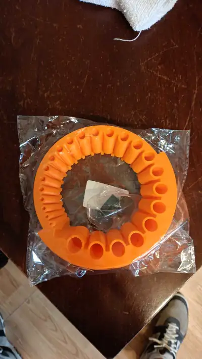This orange drill sharpening attachment, still sealed in its original packaging, is designed for eff...