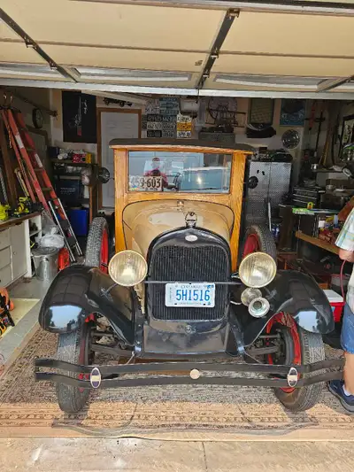 Vintage Ford Model A utility wagon has a custom wood-paneled body with a tan hood and black fenders....