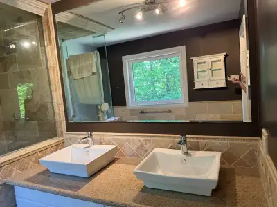 Complete double-sink bathroom vanity set and mirror removed during a renovation and ready for instal...
