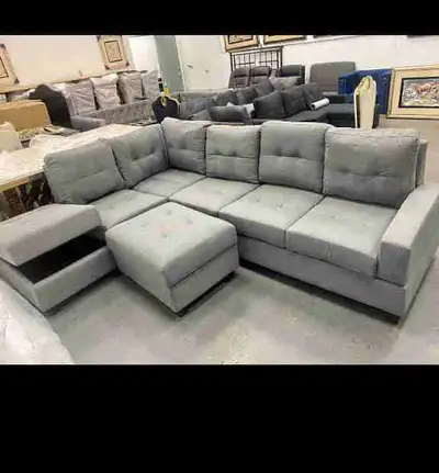 This stylish grey sectional sofa features a modular design with an ottoman, perfect for flexible arr...