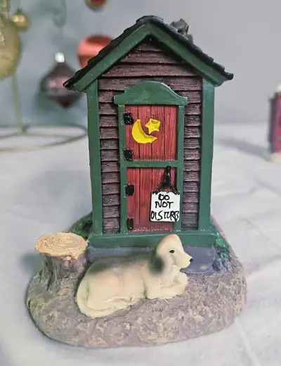 This charming outhouse figurine features delightful details such as a 'Do Not Disturb' sign, a cresc...