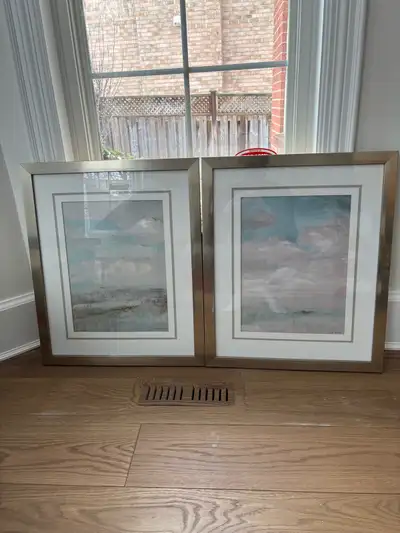I'm selling a set of two framed paintings, each featuring a serene abstract landscape with soft blue...