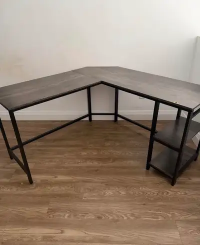 This L-shaped desk features a sleek, dark wood-grain finish and a sturdy black metal frame, compleme...