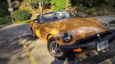 A well-preserved 1977 MGB black soft top convertible with its original Sand Glow paint (a distinctiv...
