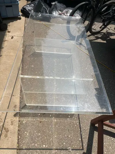 This is a used, clear coffee table with a modern design, perfect for any living room. It features a...
