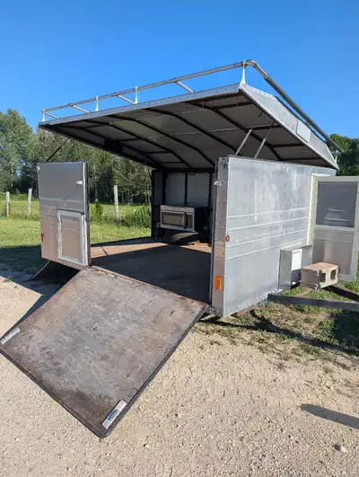This used enclosed trailer features a functional fold-up roof design and a rear ramp, offering versa...