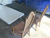 A pair of folding tables and wooden chairs